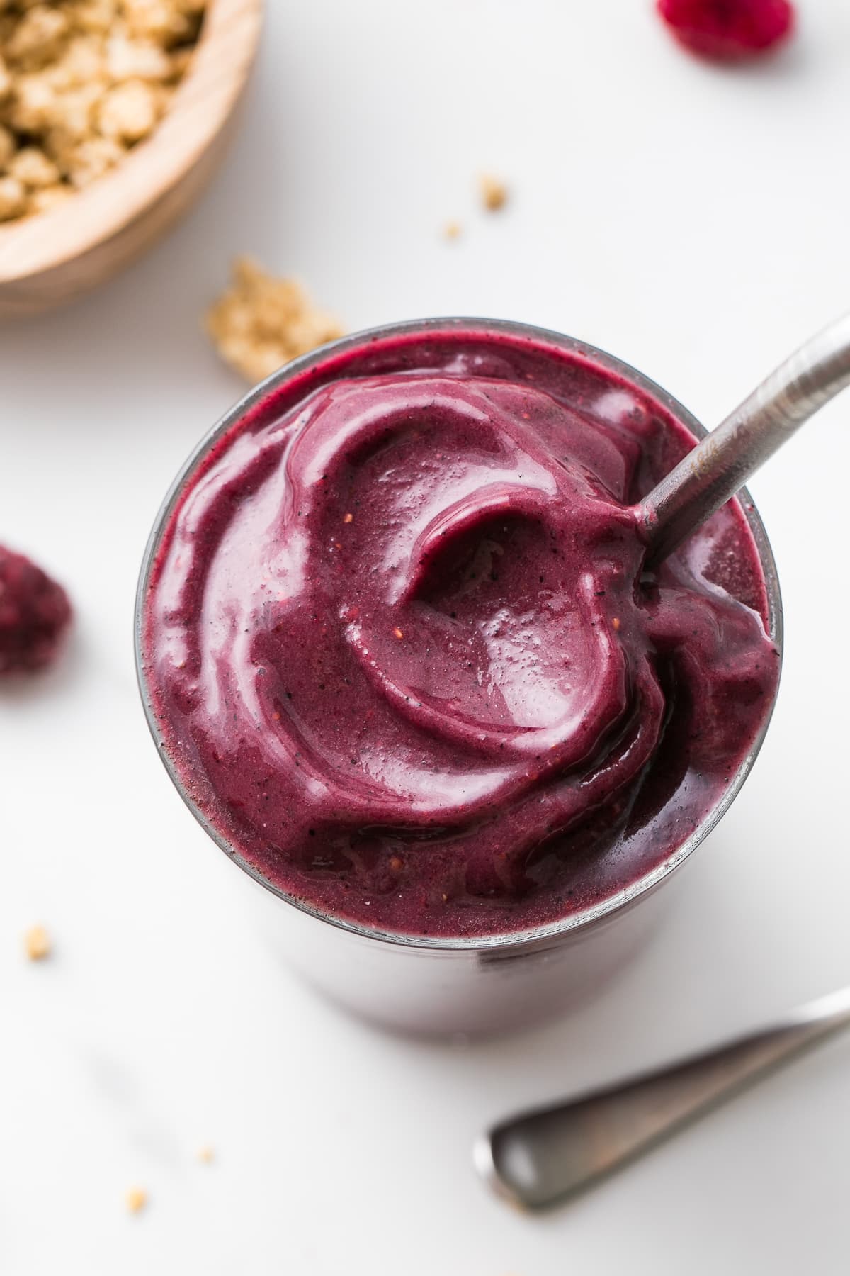 side angle view of acai smoothie with straw and items surrounding.