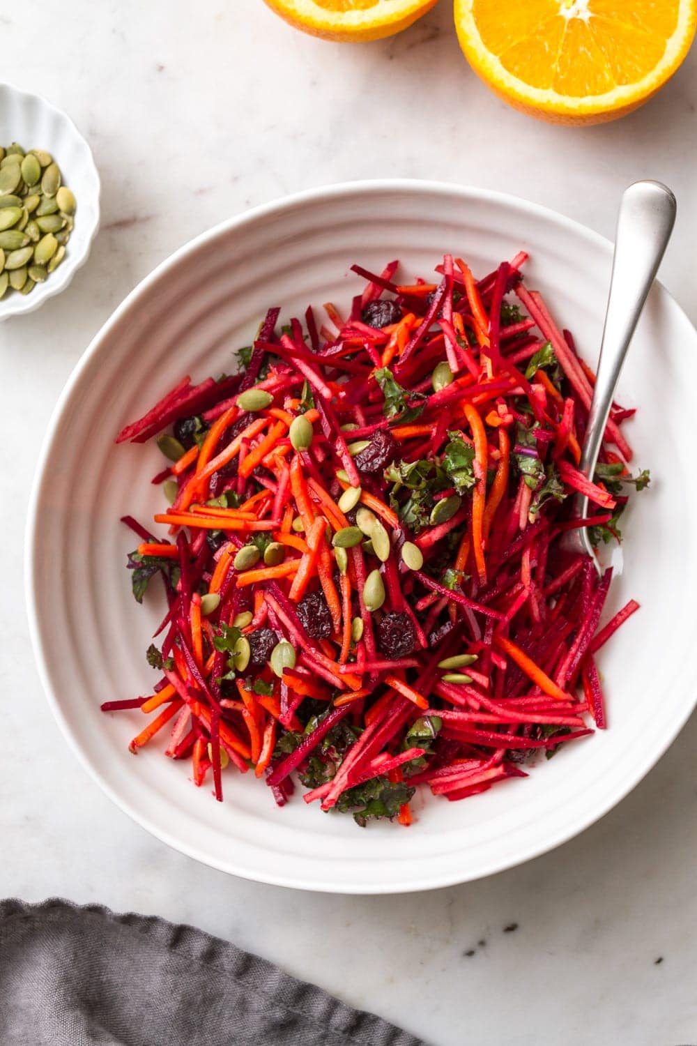 apple beet carrot kale salad with orange dressing in white serving bowl