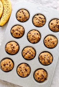 top down view of vegan banana chocolate chip muffins just pulled from the oven in a muffin tin.