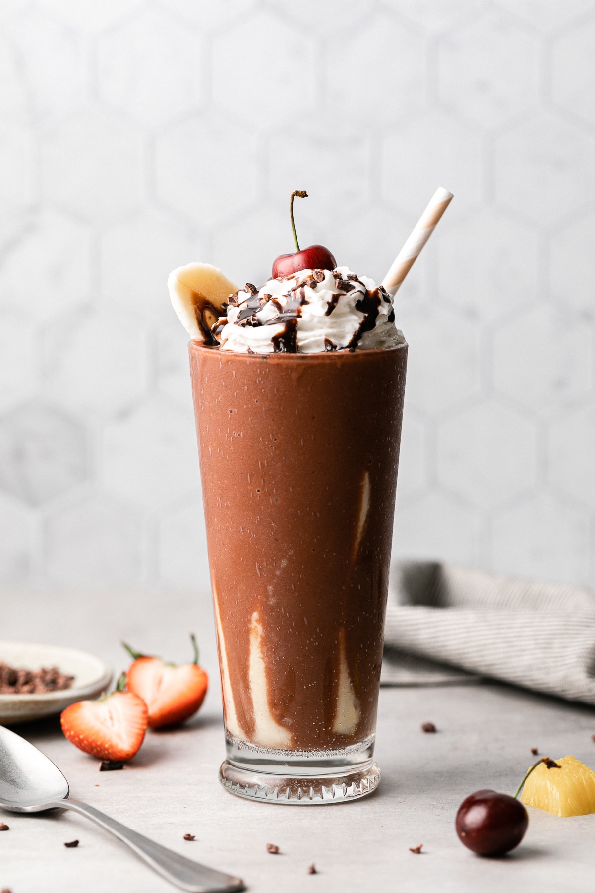 head on view of banana split smoothie in a glass with straw.