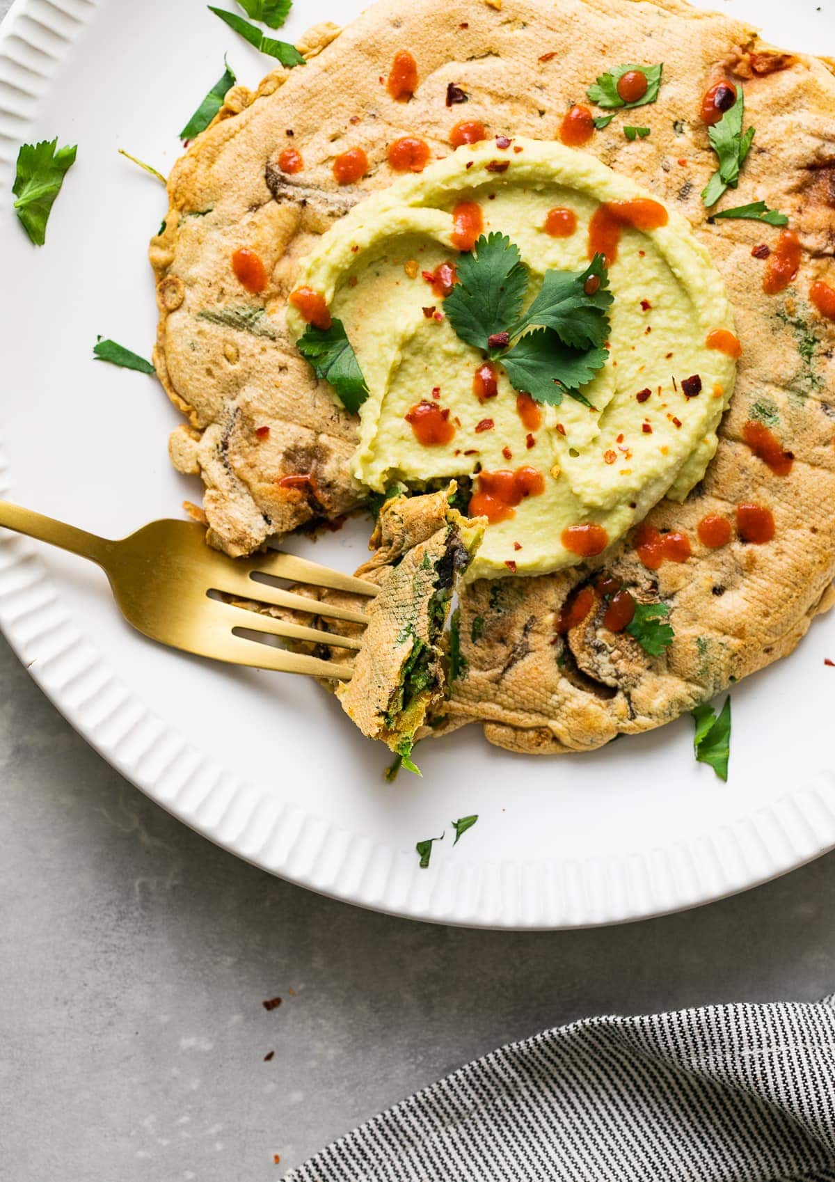 top down view of savory chickpea pancake on a white plate with fork.