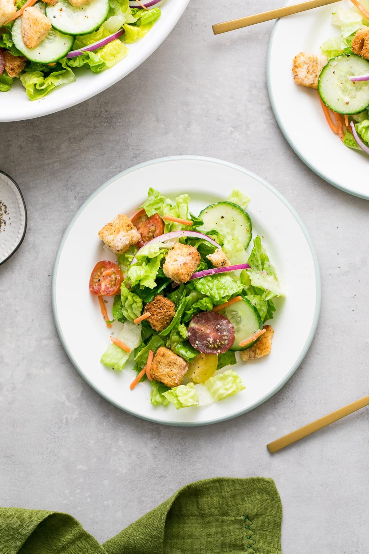 top down view of house salad on small plate with items surrounding.