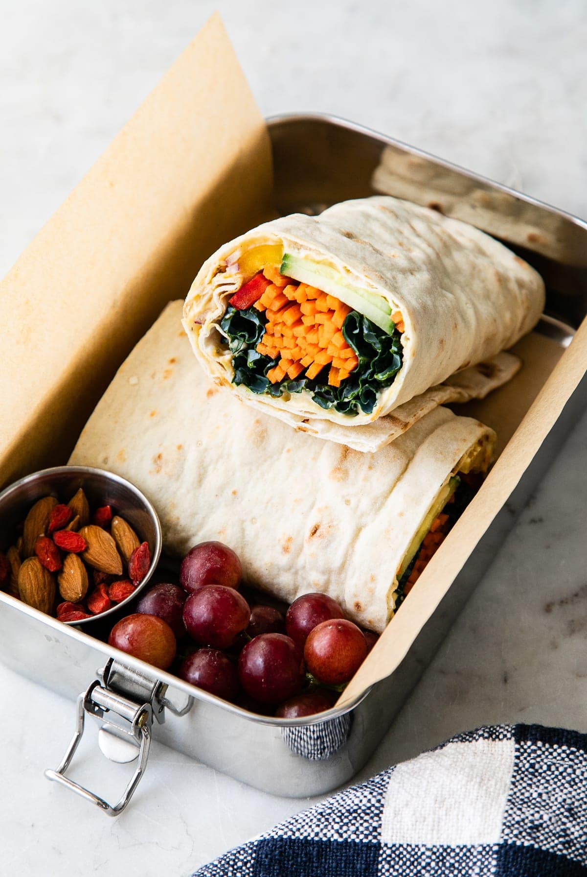 top down view of metal bento box with hummus veggie wrap and other items.