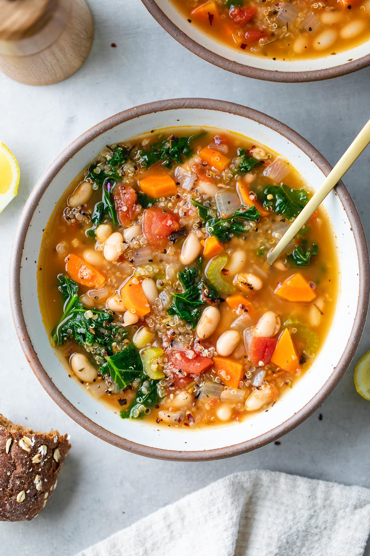 top down view of bowl with serving of kale, quinoa and white bean soup with spoon.