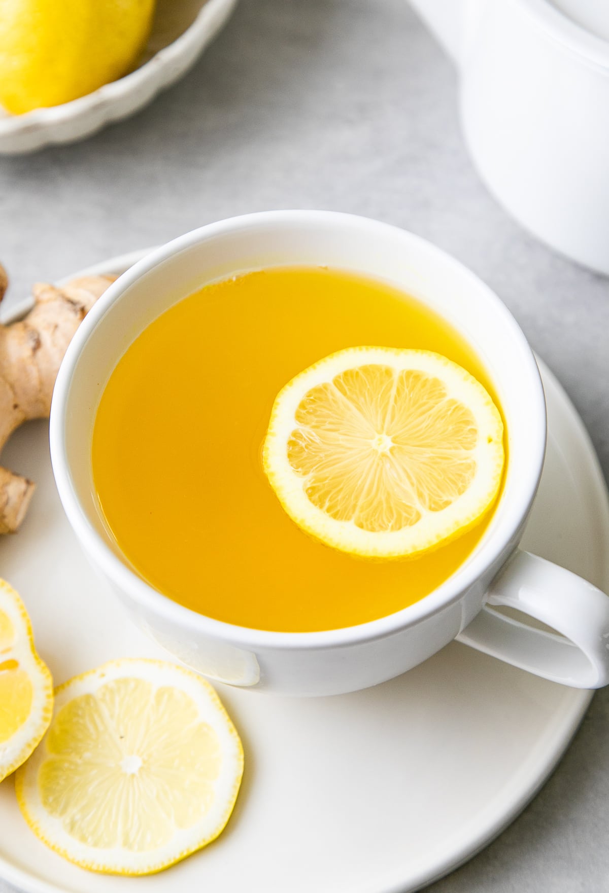 top down view of lemon ginger detox tea in a cup with lemon and items surrounding.