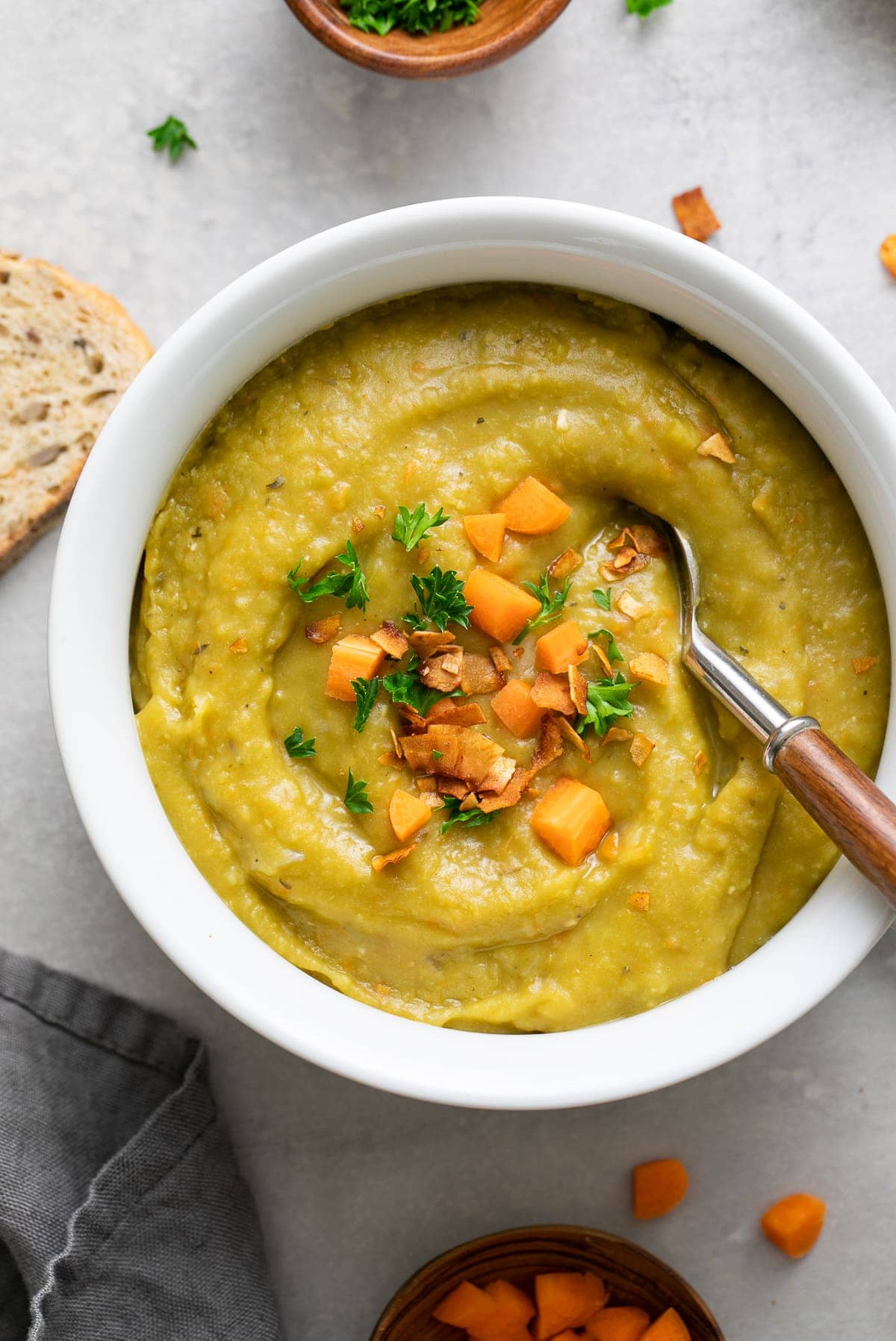 top down view of white bowl with serving of parsnip split pea soup with items surrounding.