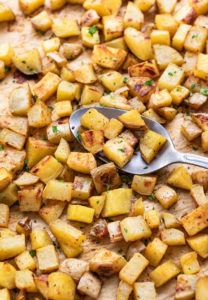 side angle view of freshly make oven roasted breakfast potatoes on a baking sheet.