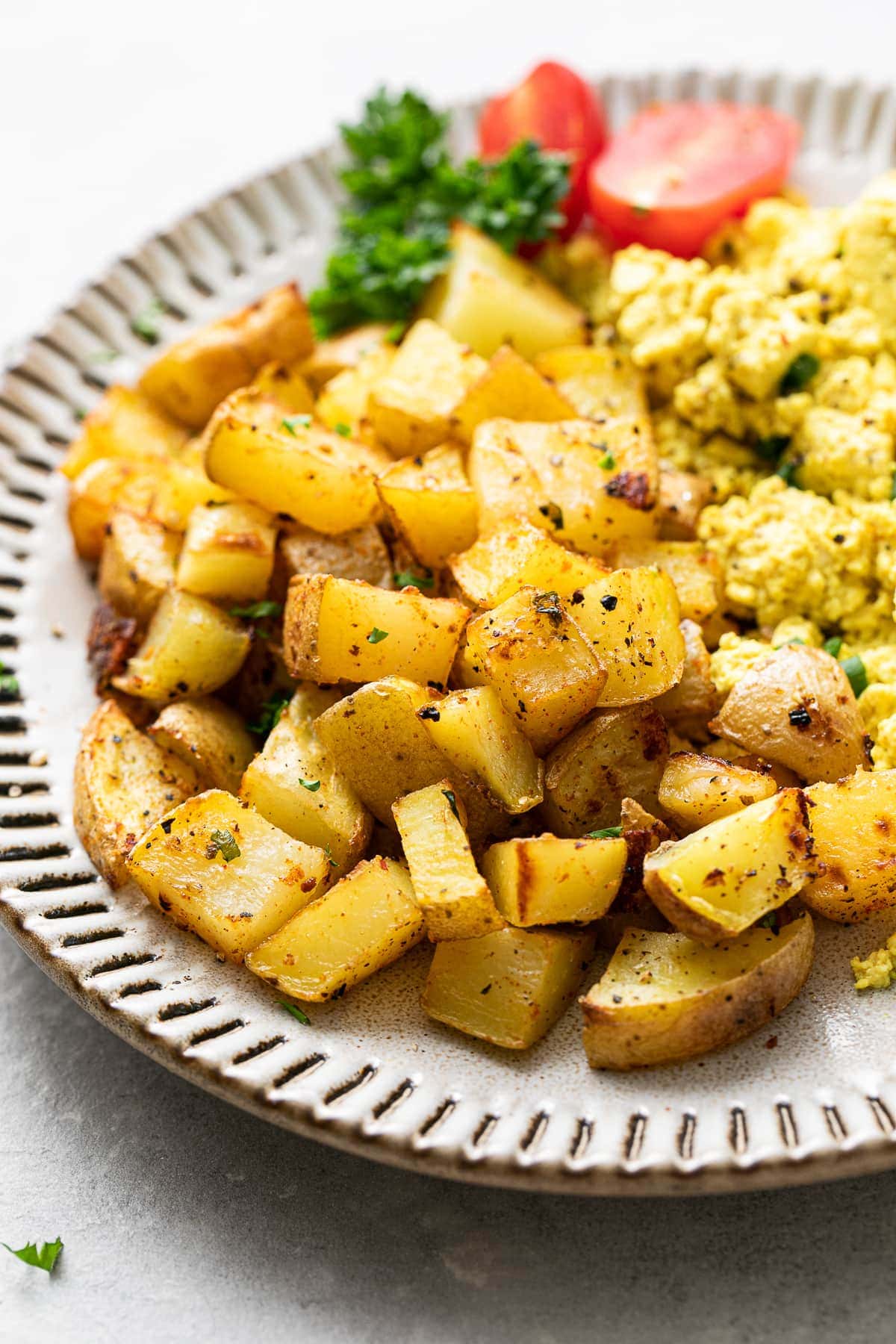 side angle view of a small plate with roasted breakfast potatoes and other items.