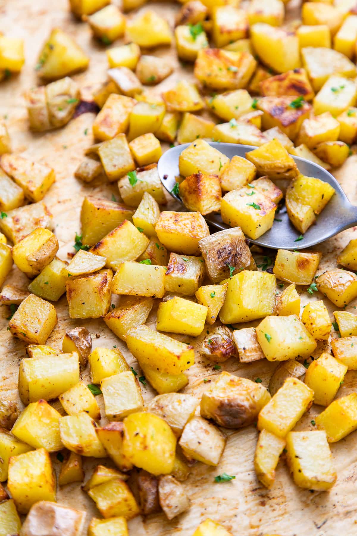 side angle view of freshly make oven roasted breakfast potatoes on a baking sheet.