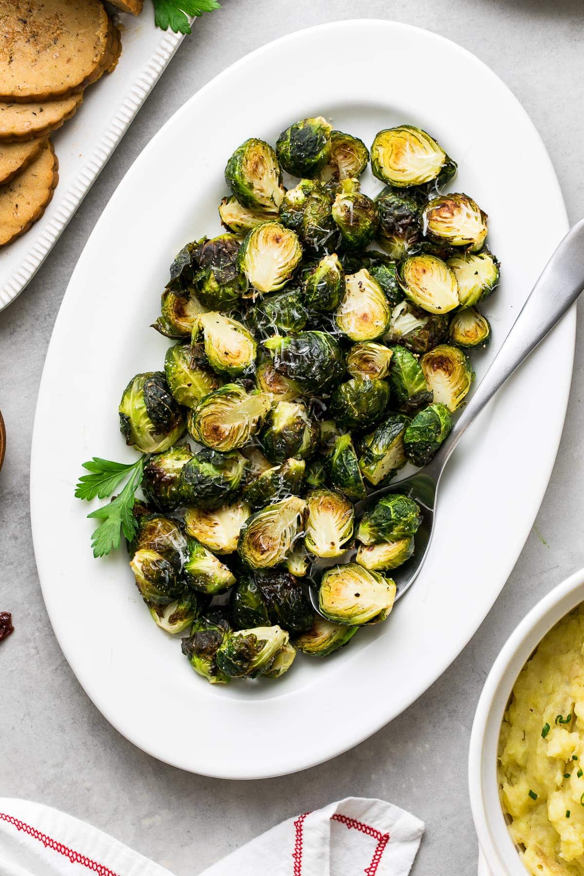 top down view of serving platter with roasted brussels sprouts with items surrounding.