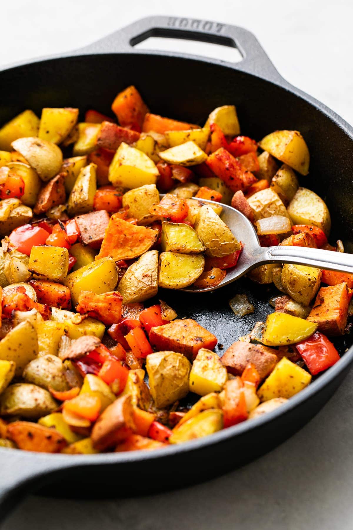 side angle view of freshly made gold and sweet potatoes in a skillet.