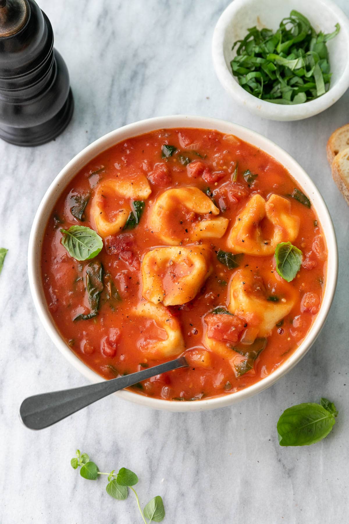 up close view of tomato tortellini soup in a bowl with spoon.