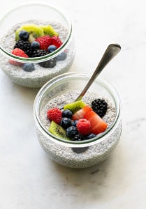 side angle view of glass jar with serving of chia pudding and fresh fruit with spoon.