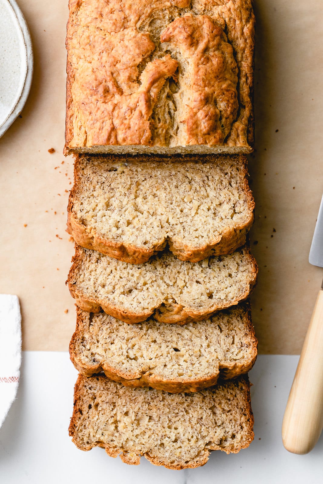 top down view of sliced vegan banana bread with items surrounding.