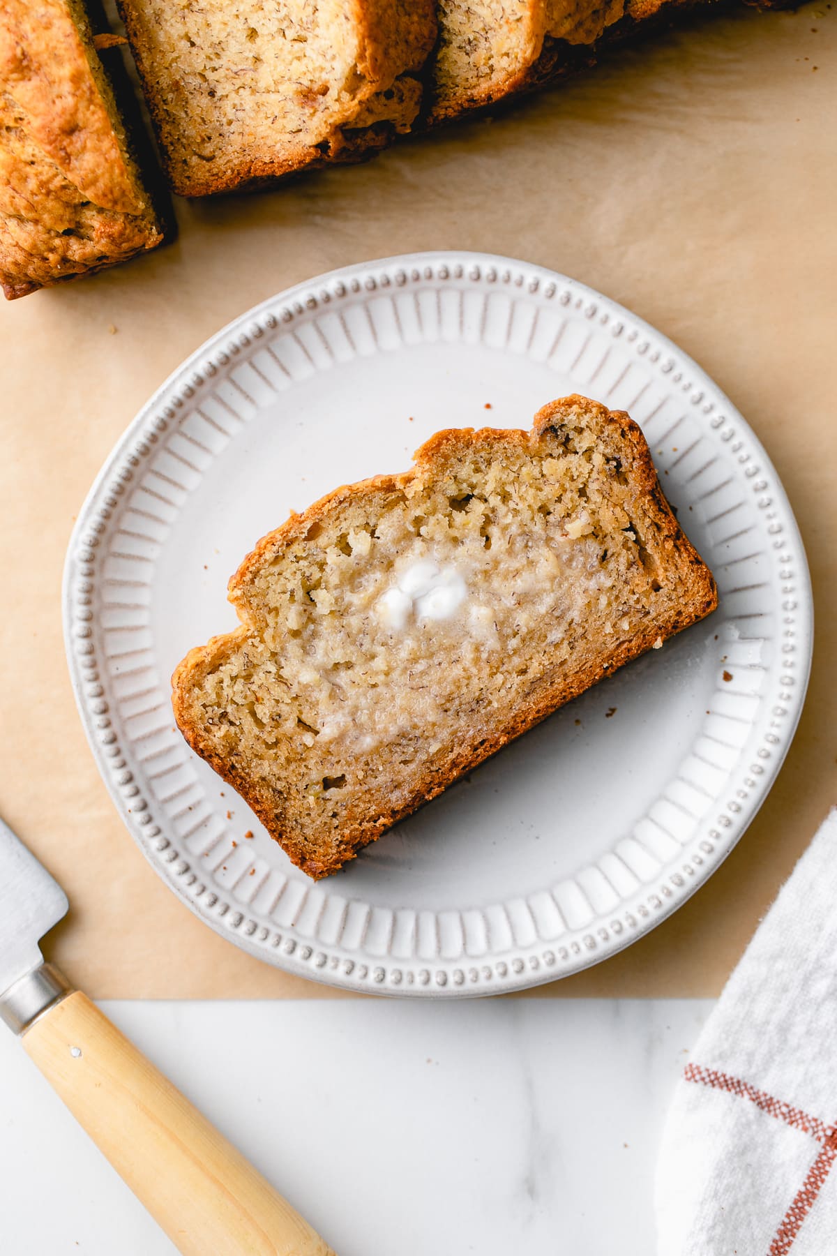 top down view of plate with slice of banana bread with butter.