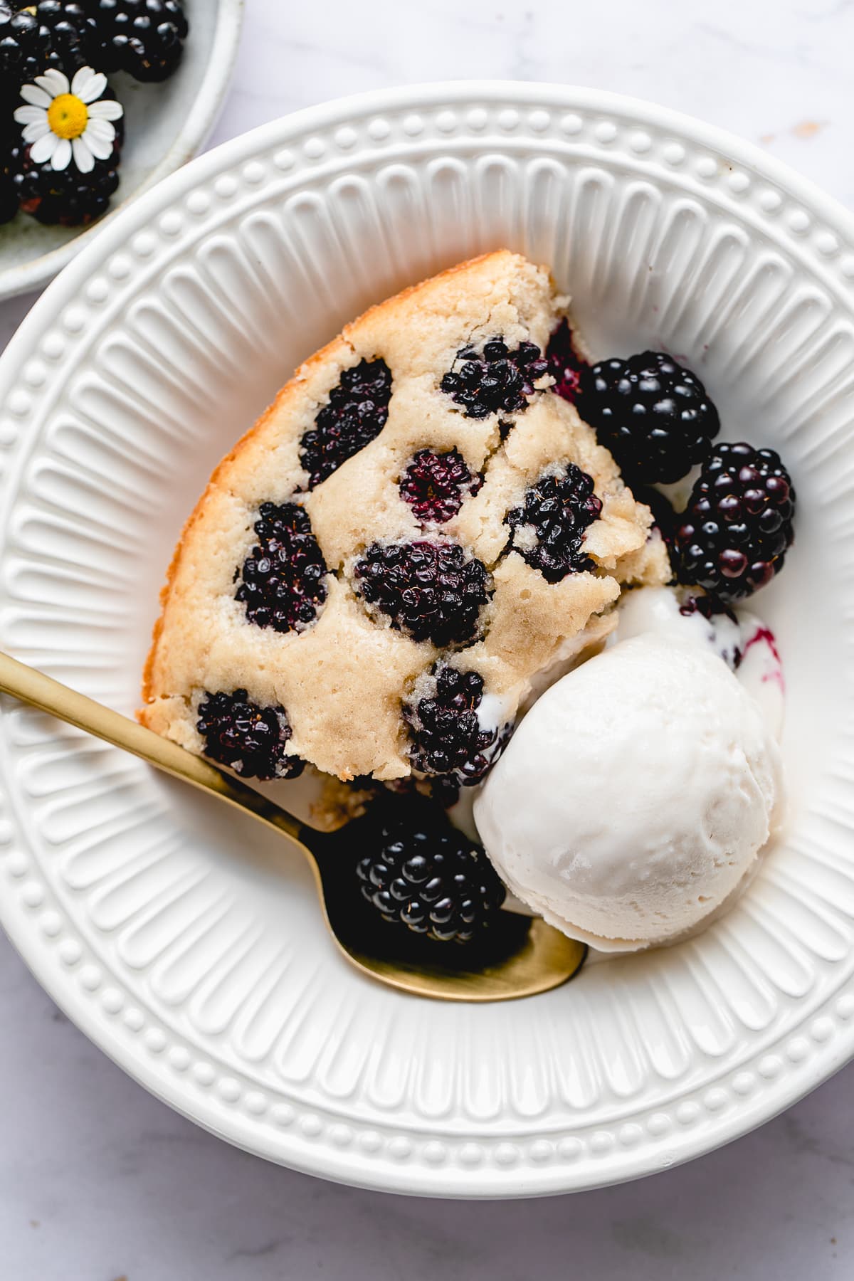 top down view of plated vegan blackberry cobbler in a bowl with scoop of ice cream.