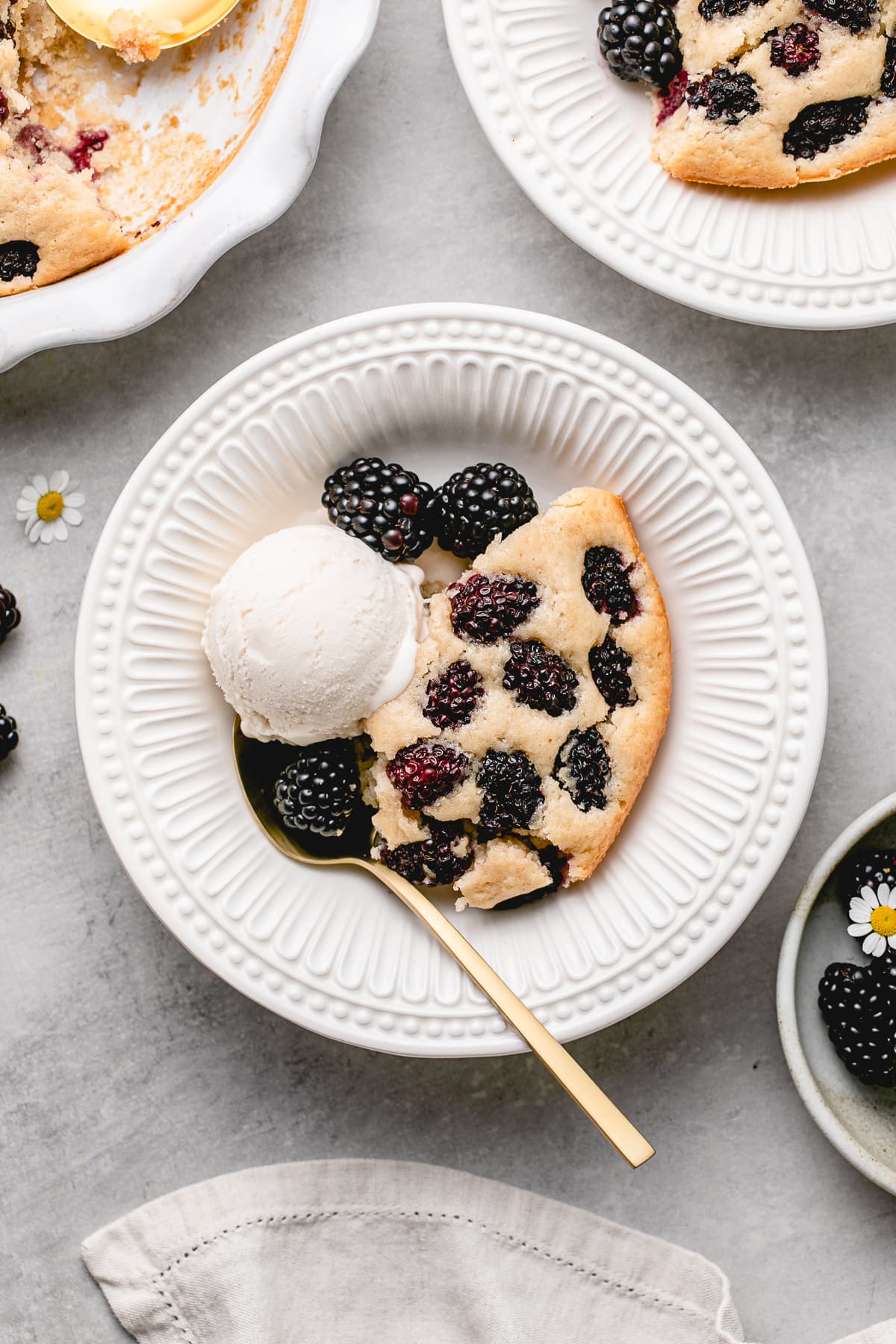 top down view of plated vegan blackberry cobbler in a bowl with scoop of ice cream.