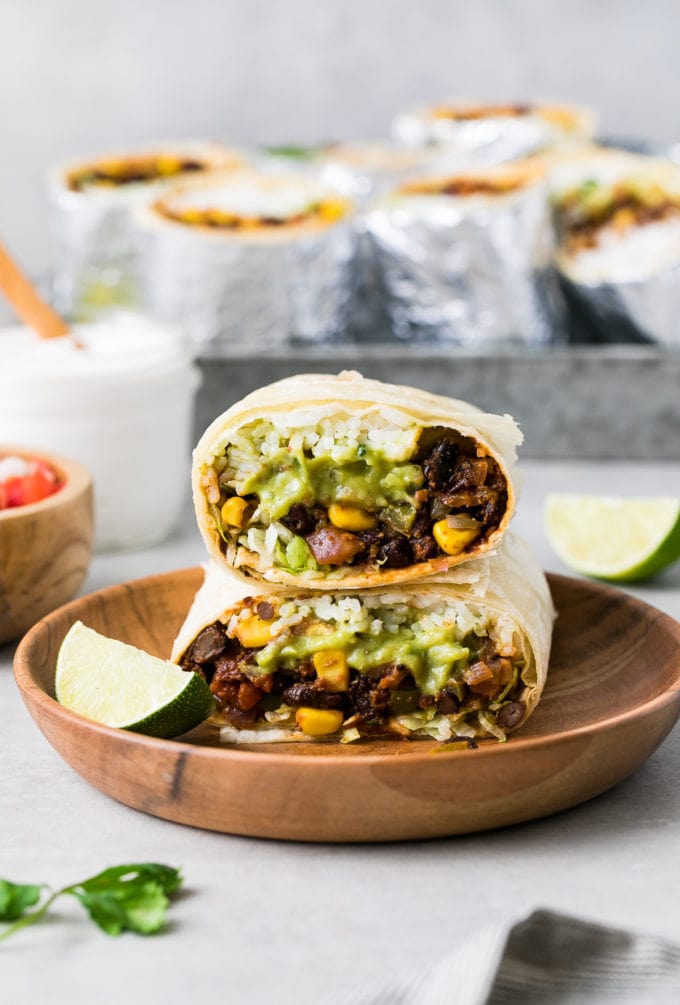 head on view of 2 halves of vegan burrito stacked on each other with items surrounding.