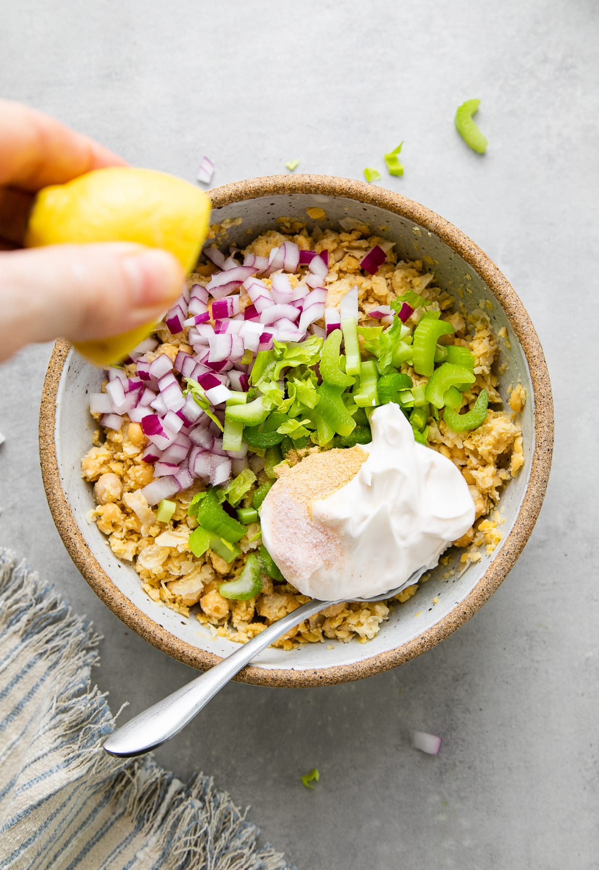 top down view of ingredients added to mashed chickpeas with squeeze of lemon being added.