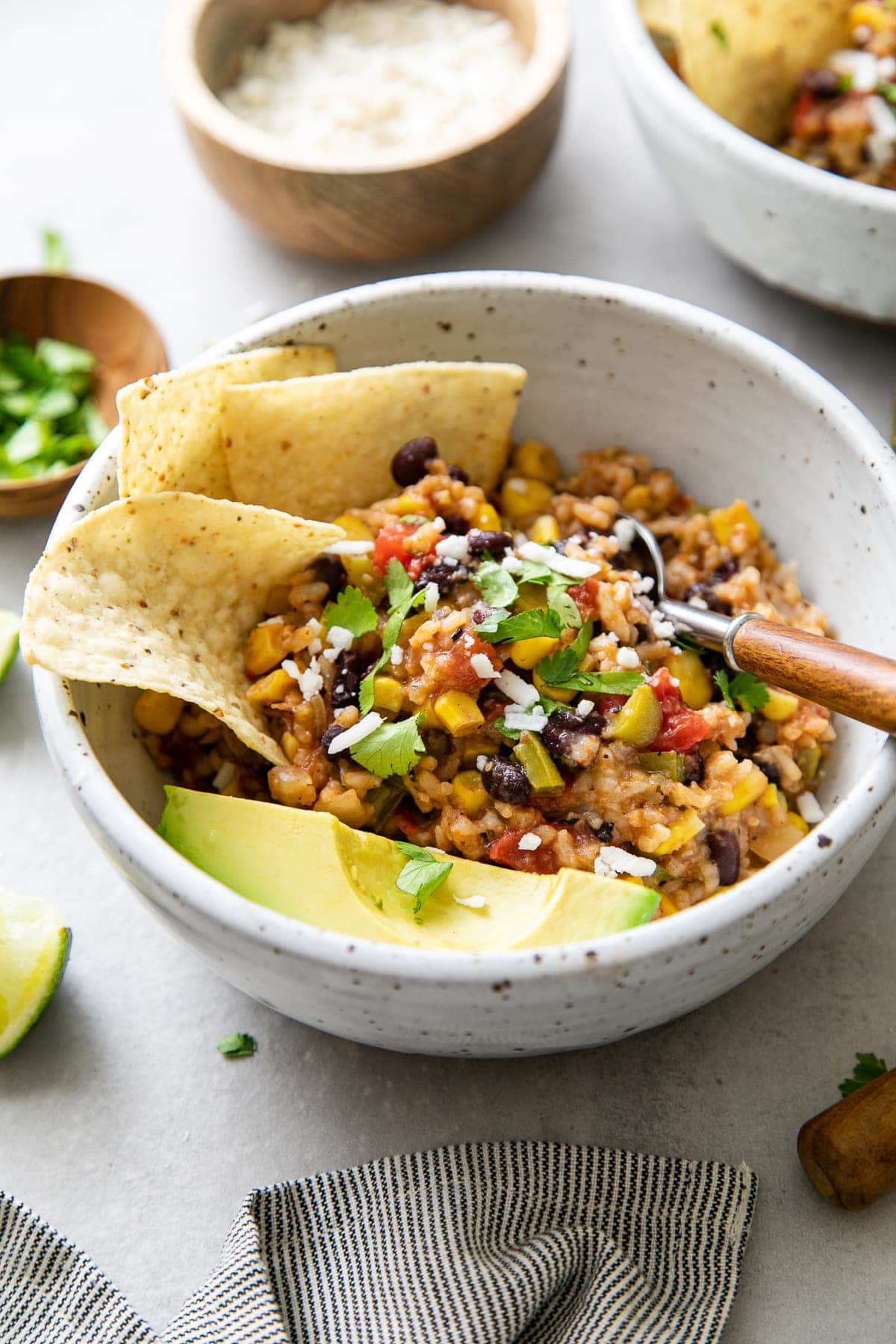 side angle view of bowl with serving of vegan enchilada rice with extras and items surrounding.