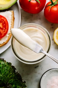 homemade vegan mayonnaise in a mason jar with butter knife ready to spread