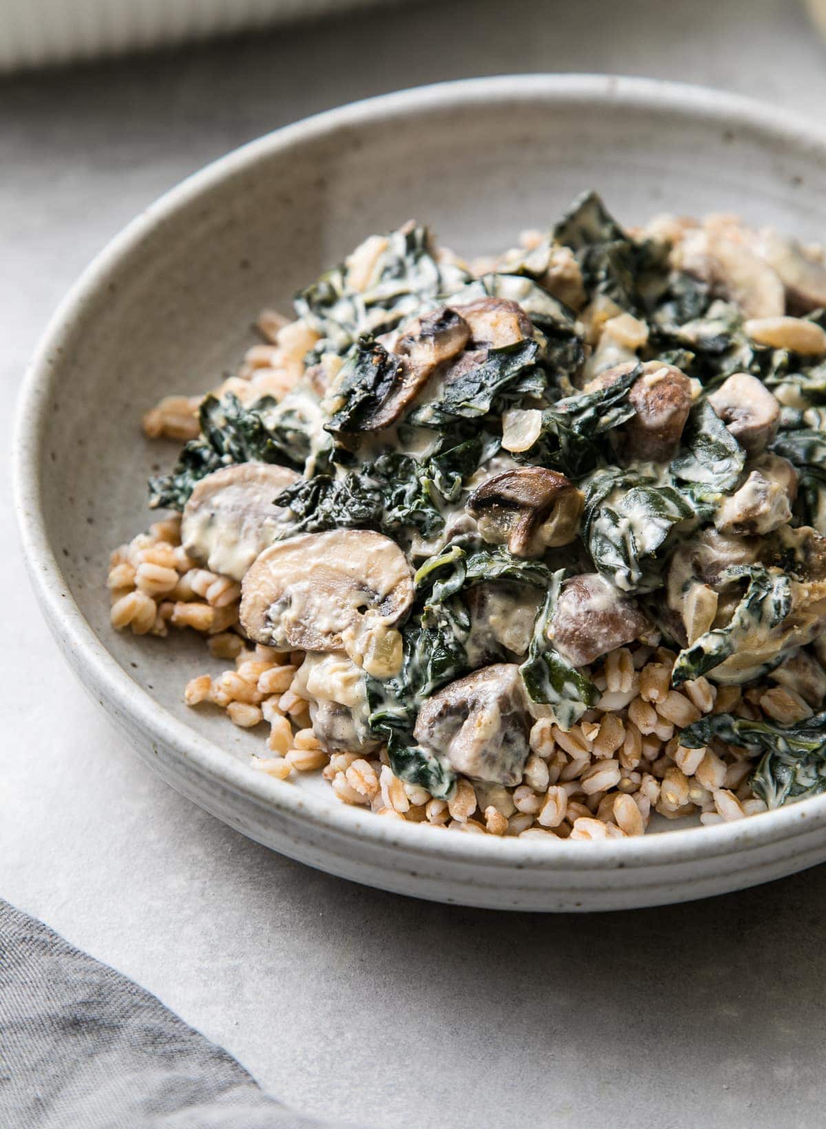 side angle view of vegan mushroom gratin with kale over a bed of farro.