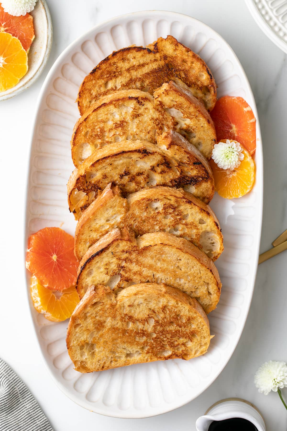 top down view of serving platter with vegan orange french toast with items surrounding.