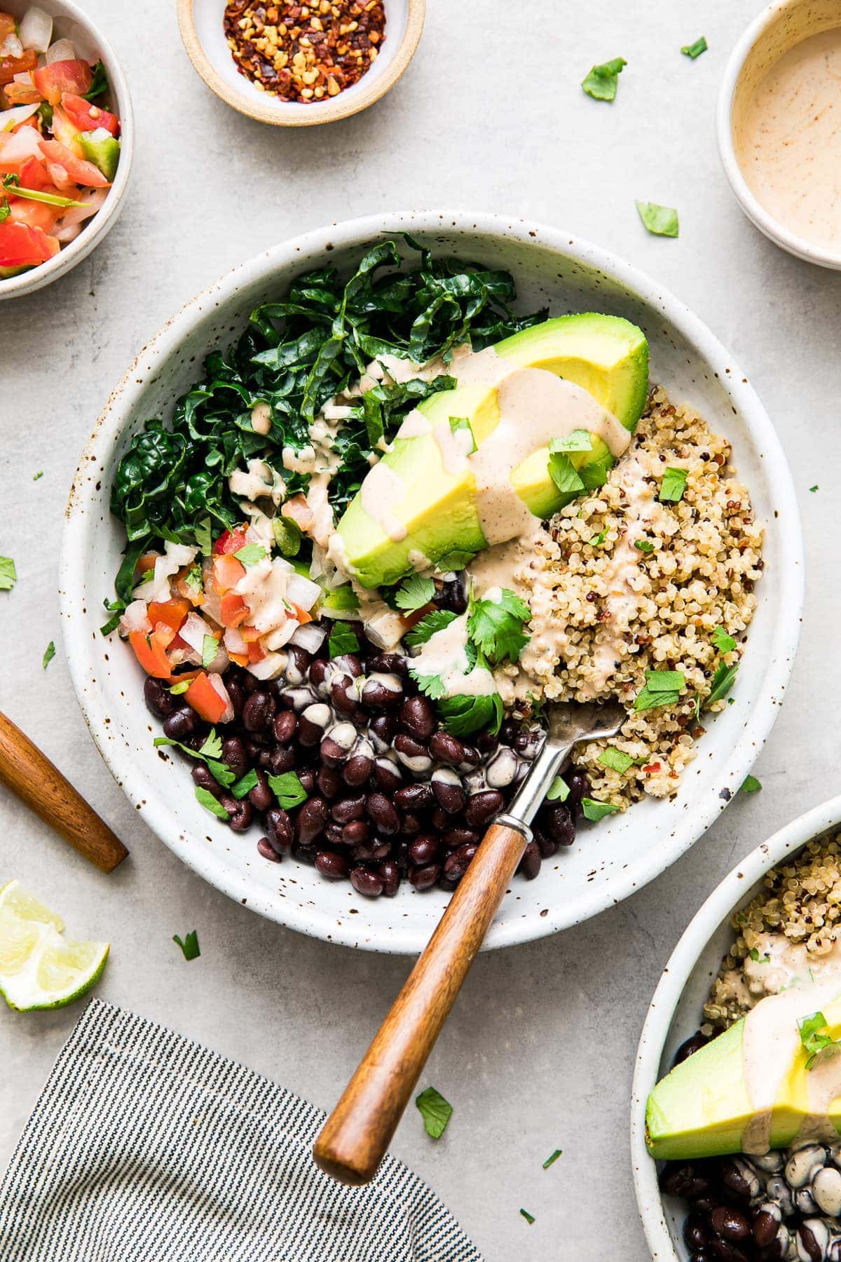 top down view black bean burrito bowl with wooden fork and items surrounding.