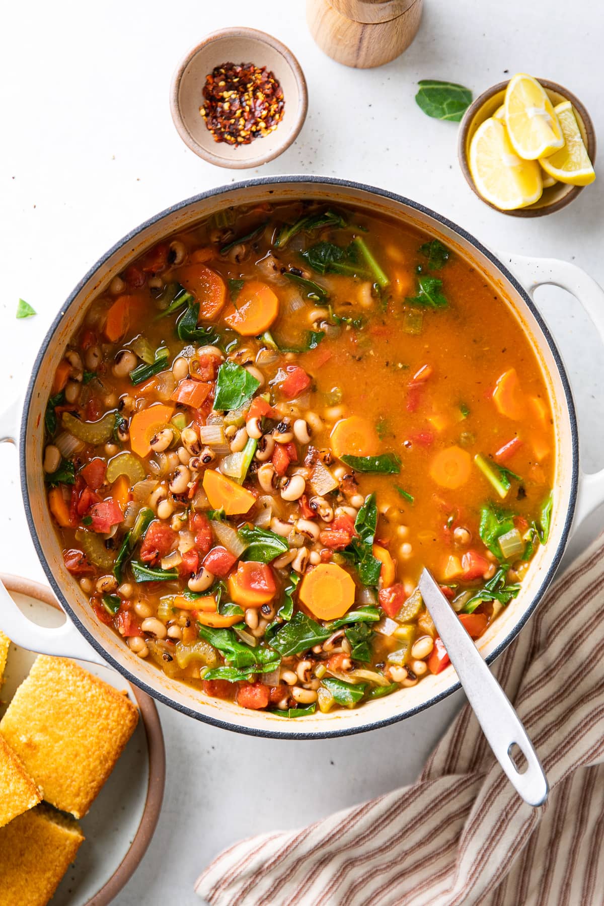 top down view of freshly made black eyed pea soup in a pot with items surrounding.