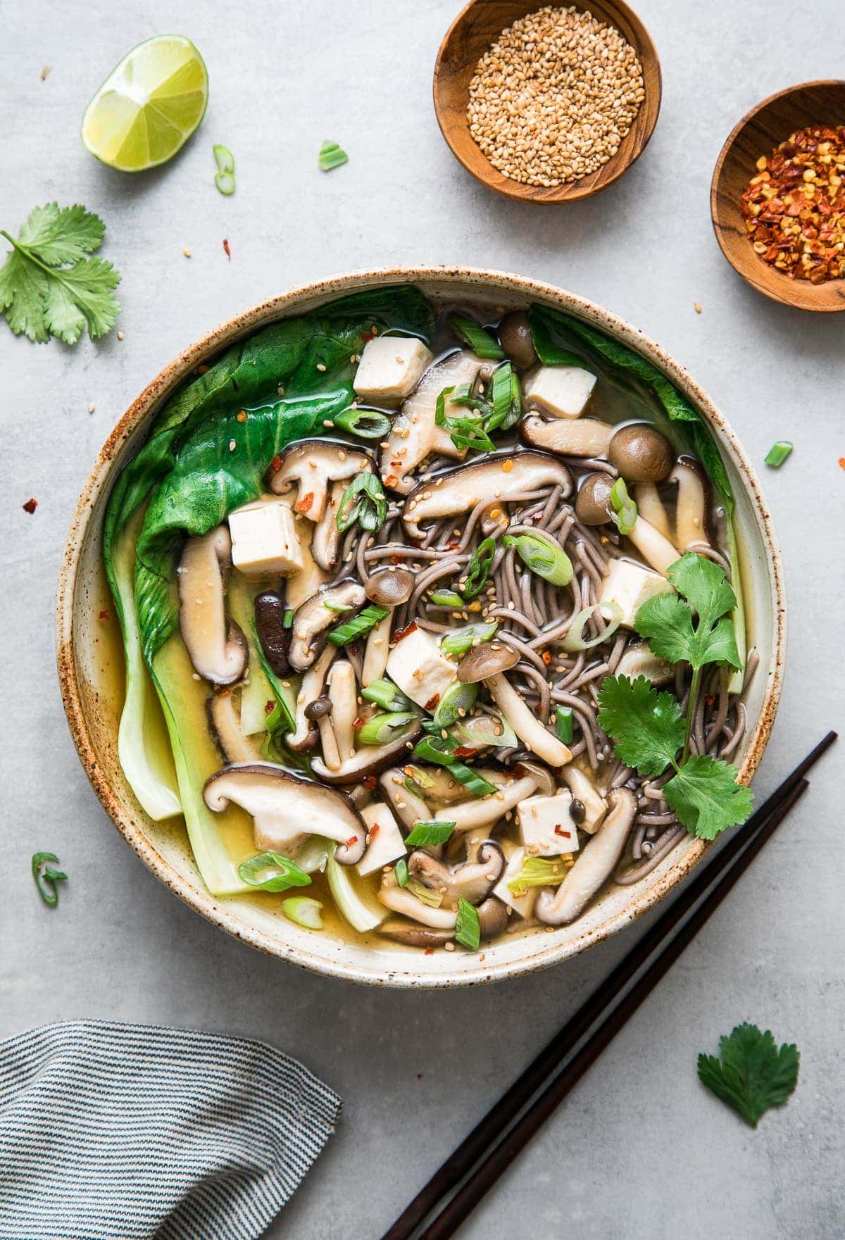 top down view of a bowl with serving of soba noodle soup with bok and mushrooms.