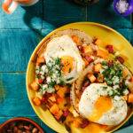 Breakfast Tacos on a plate with chorizo hash Fried eggs, tortillas, beans and coffee on the side