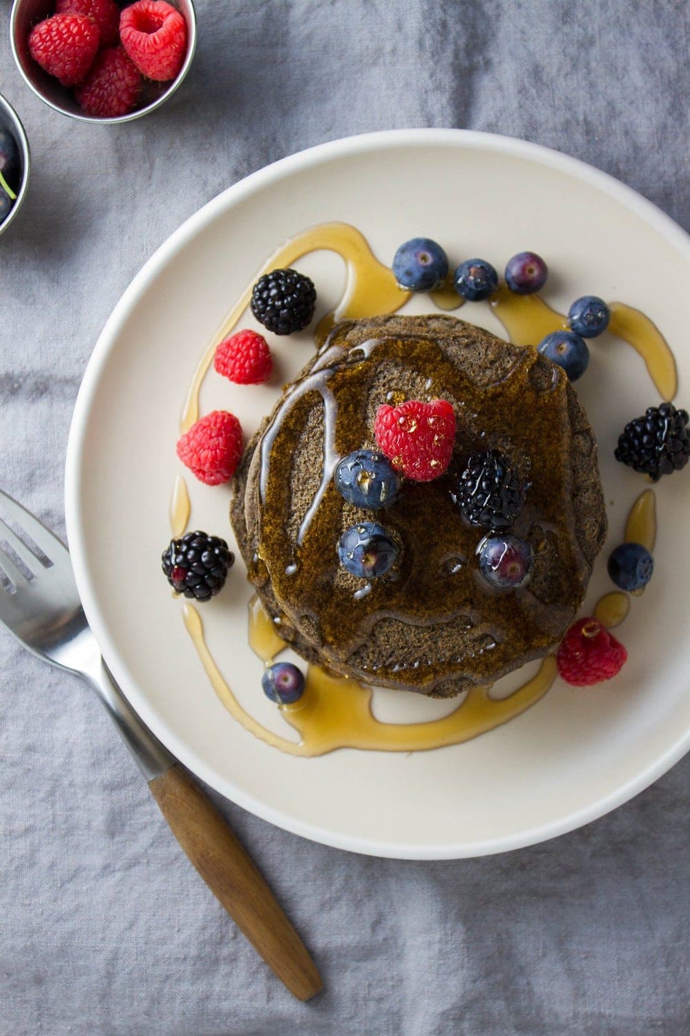 top down view of a stack of pancakes topped with berries and pure maple syrup