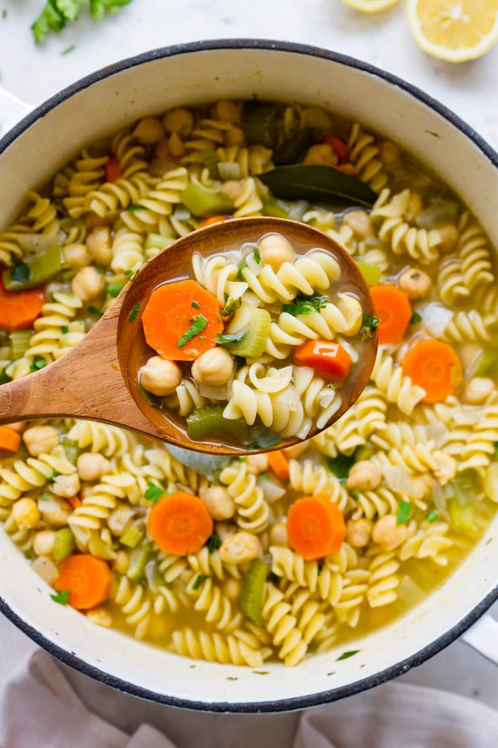 top down view of a wooden spoon filled with hearty vegan chickpea noodle soup.