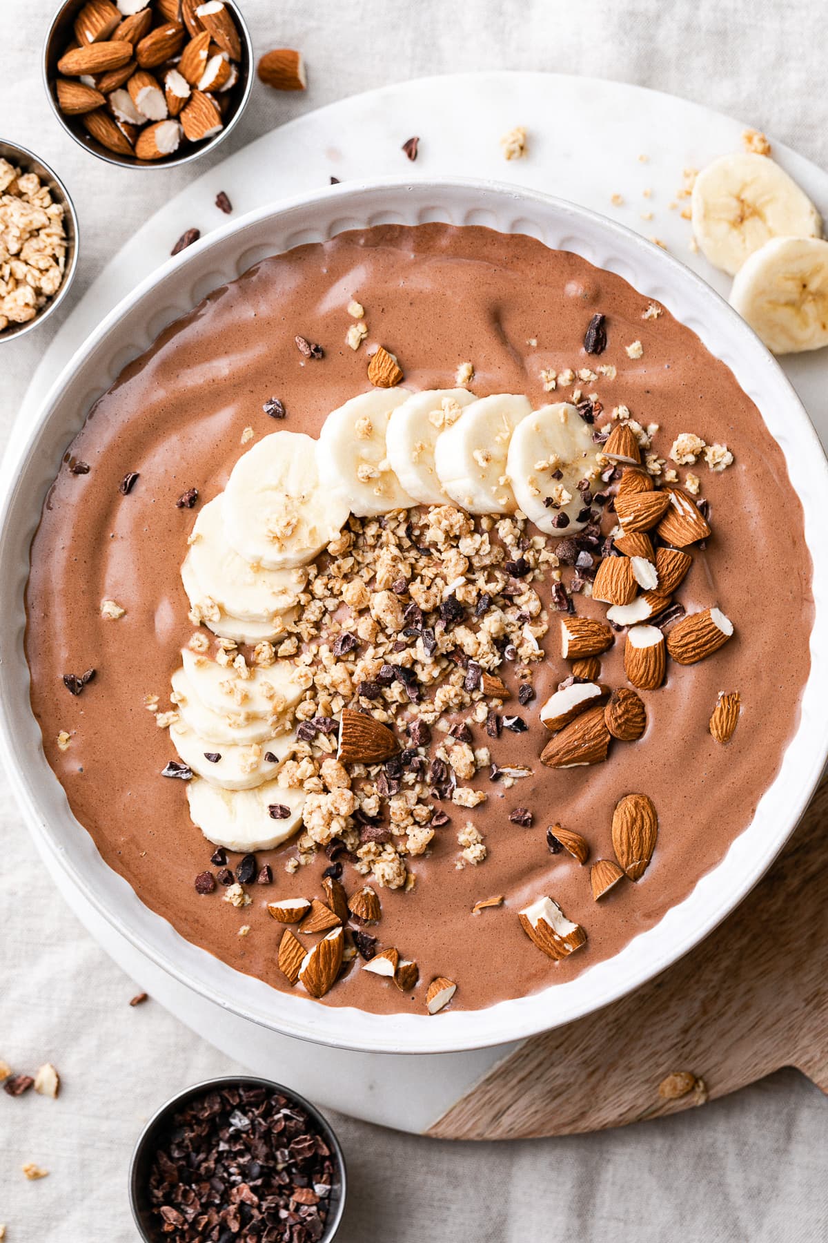 top down view of chocolate almond butter smoothie in a bowl with items surrounding.