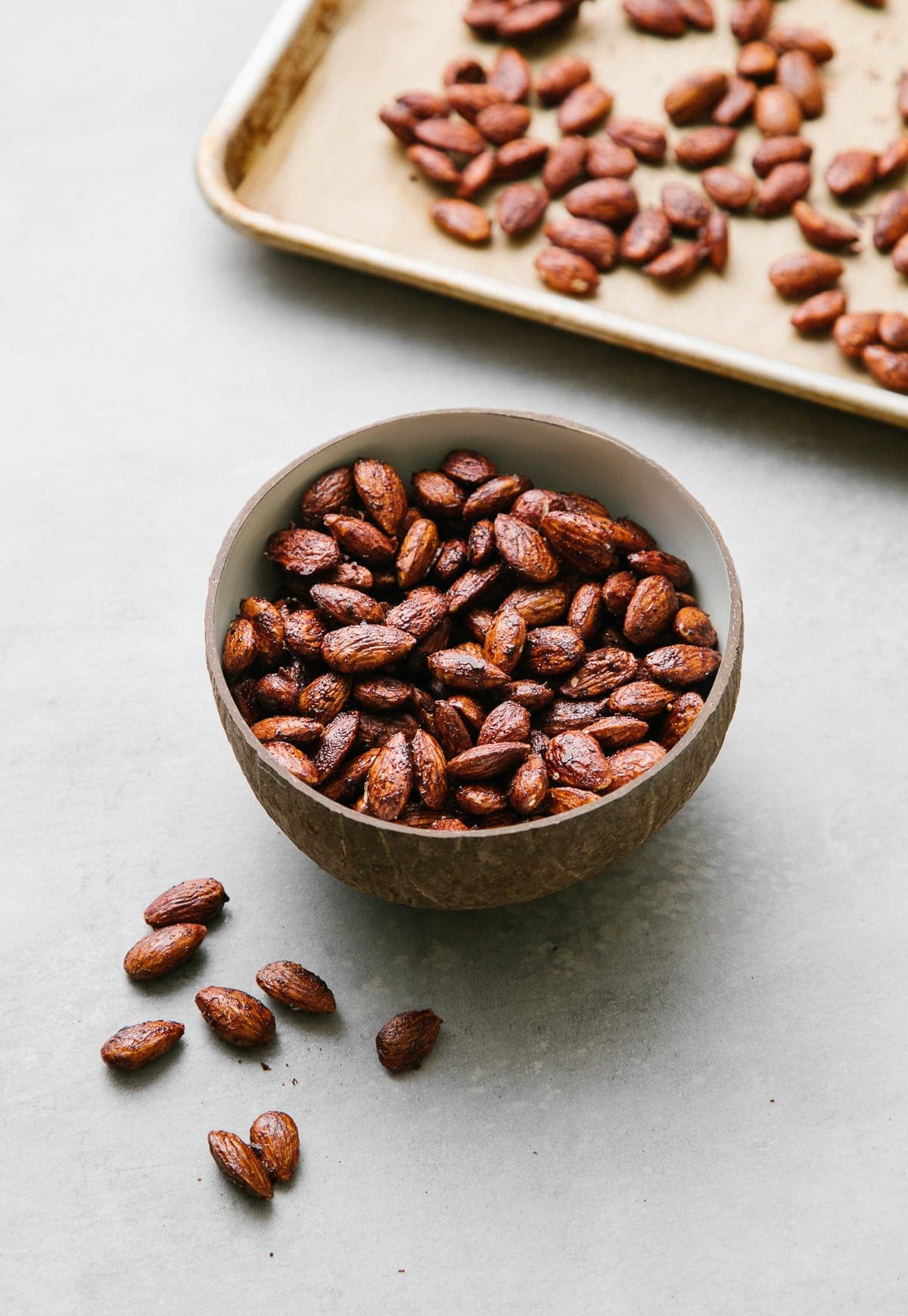 side angle view of roasted almonds glazed with a chocolate chai glaze in a small bow.