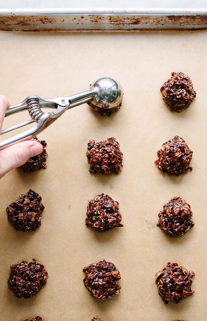 top down view of peanut butter no bake cookies being scooped and placed on a lined cookie sheet.