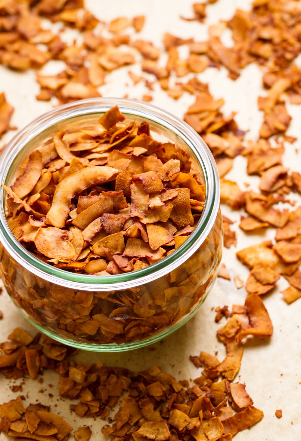 side angle view of freshly made coconut bacon in a glass mason jar.