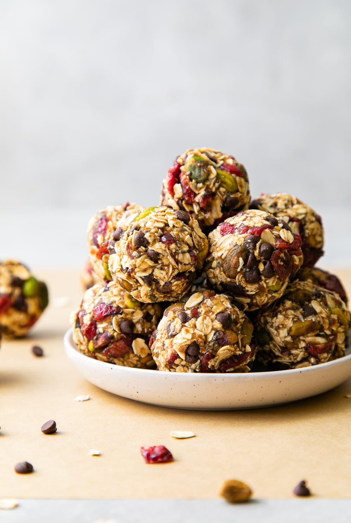 head on view of freshly rolled oatmeal energy bites with pistachios and cranberries on a plate.