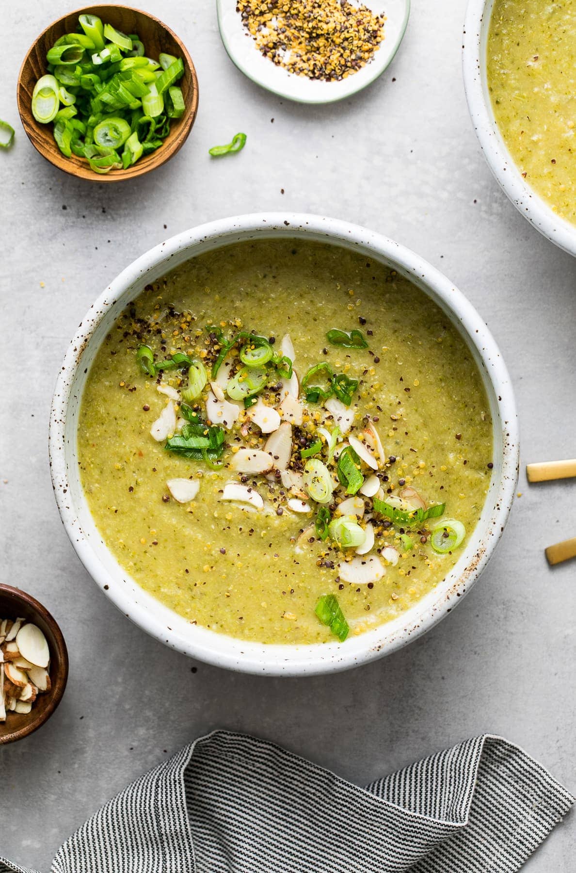 top down view of bowl of creamy broccoli red lentil soup with spoon and items surrounding.