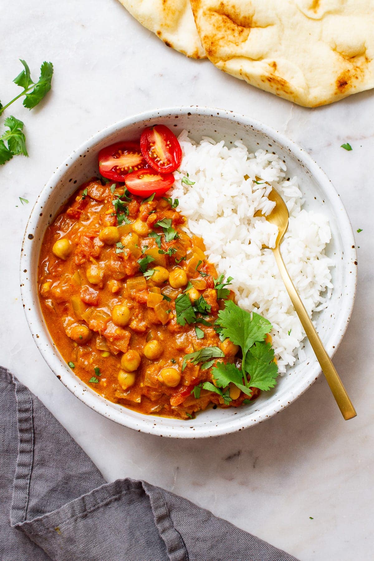 top down view of a bowl filled with a serving of easy vegan chickpea tikka masala and rice in a bowl with spoon.