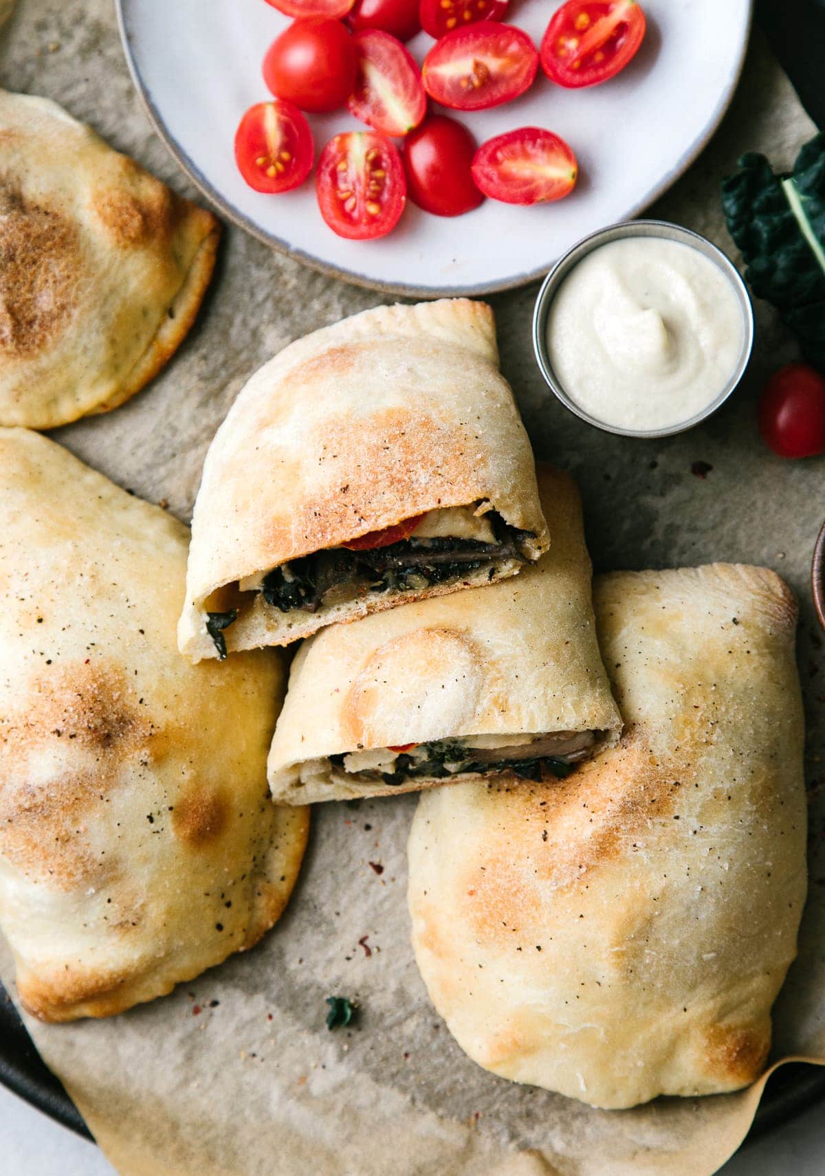 top down view of vegan calzone cut in half with items surrounding.