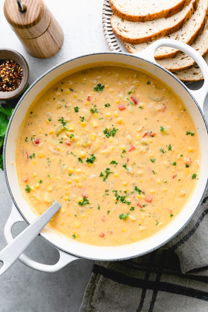 top down view of freshly made pot of vegan corn chowder with items surrounding.