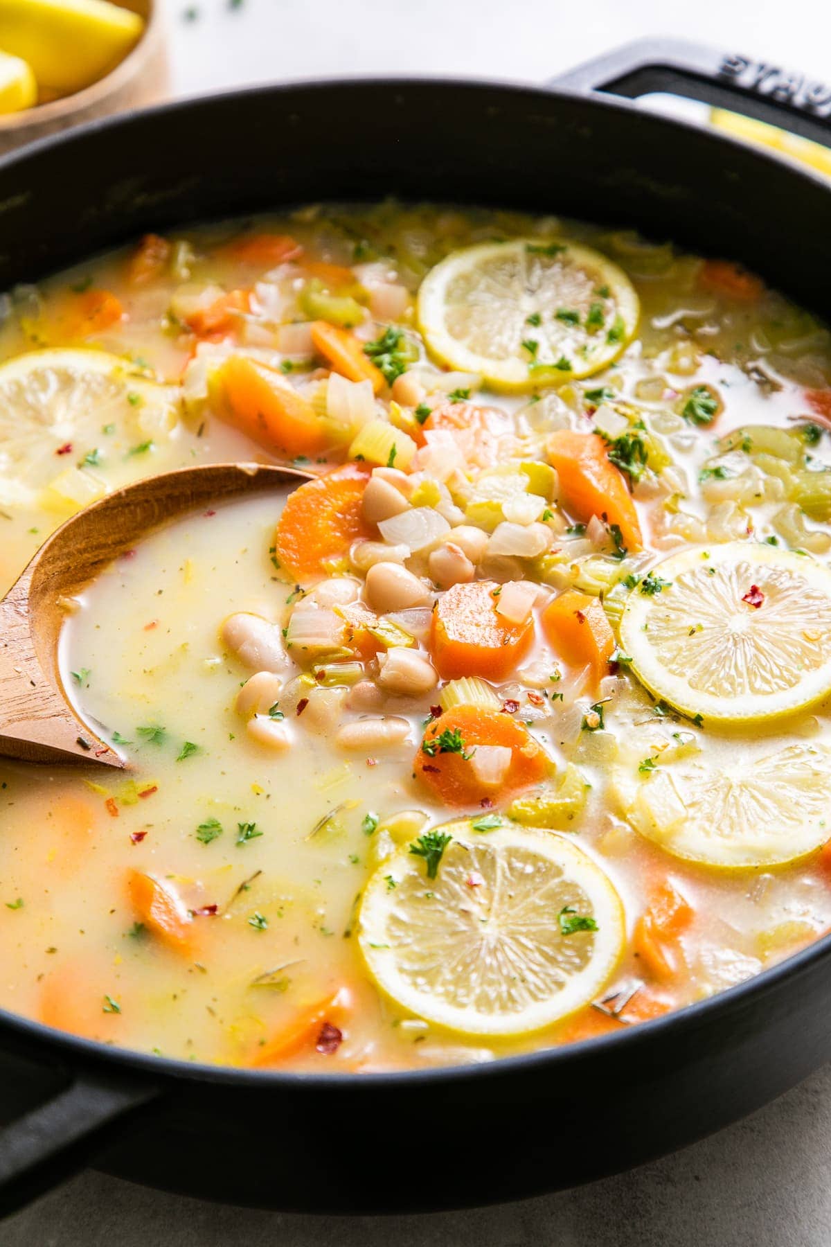 side angle view of easy white bean soup in a pot with wooden spoon.