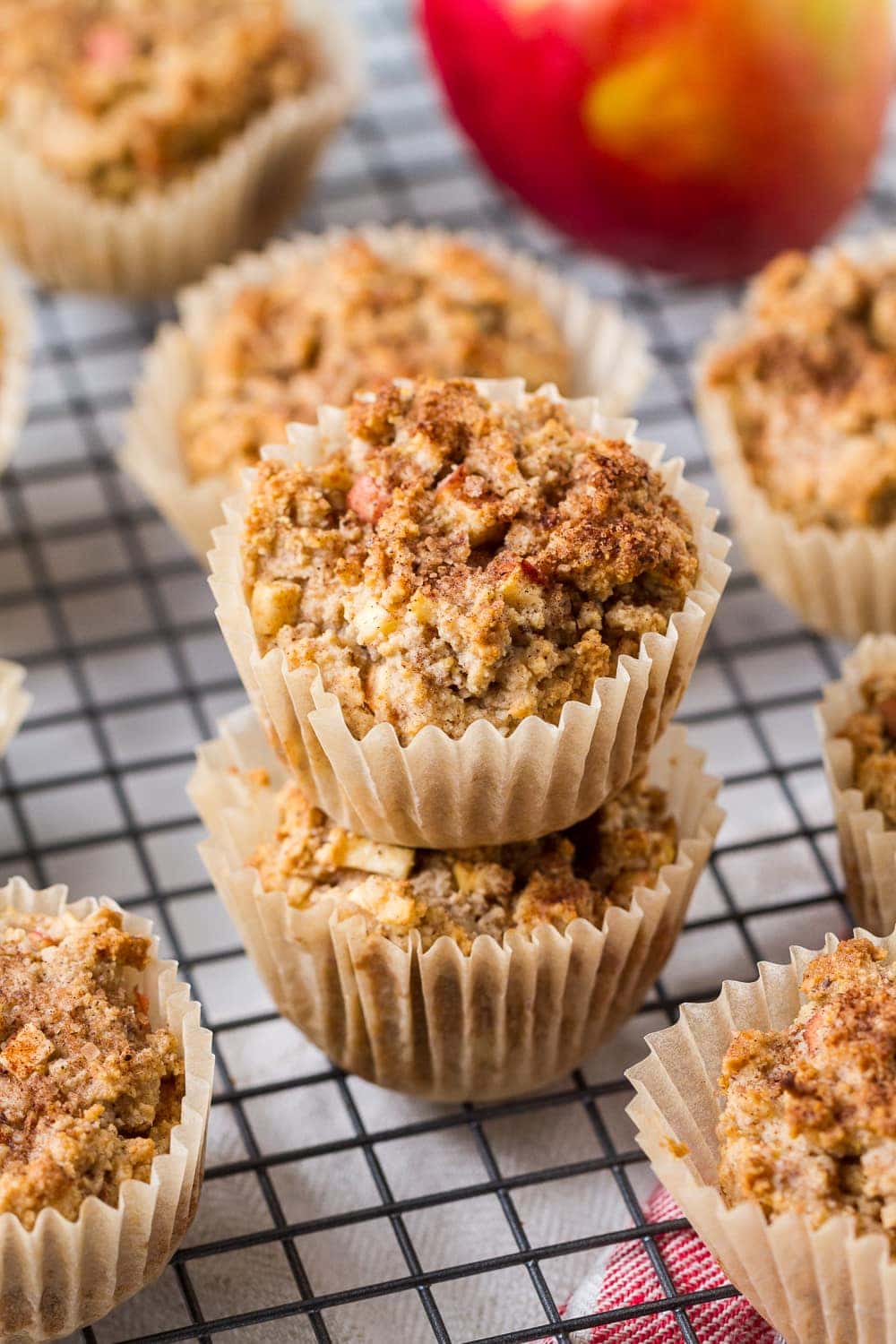 side angle view of a group of gluten free apple cinnamon muffins, with 2 stacked in the center on a wire cooling rack