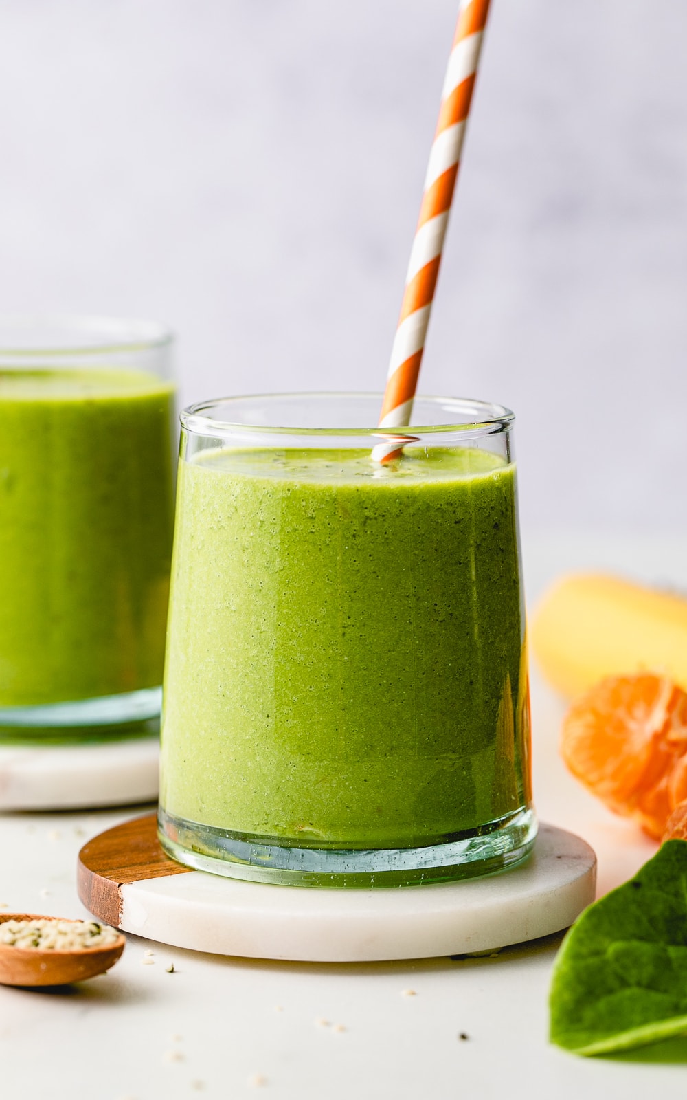 head on view of hemp smoothie in a glass with straw and items surrounding.