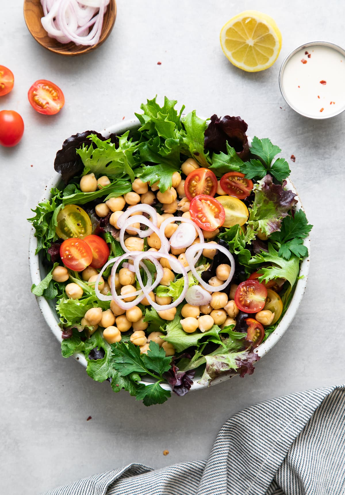 top down view of freshly made green salad with chickpeas before adding tahini dressing.