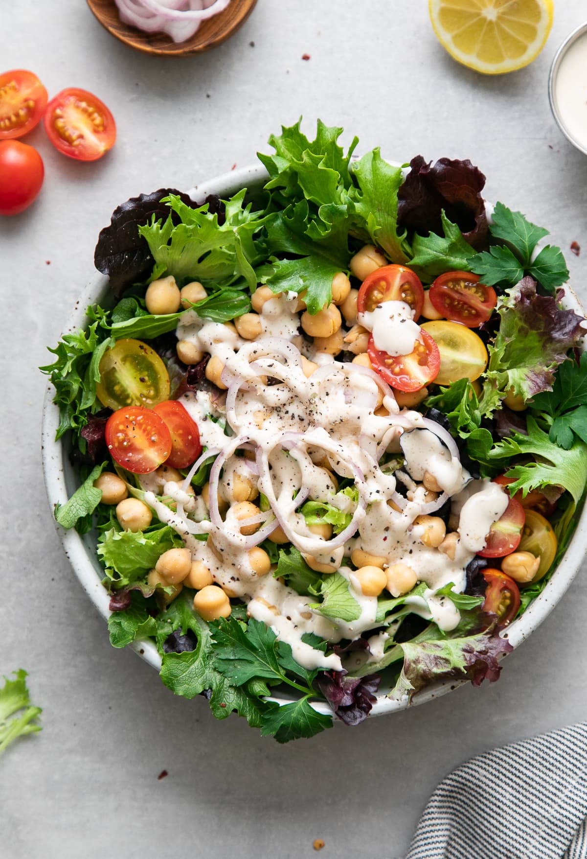 top down view of leafy green salad with chickpeas and dressed with lemony tahini dressing.