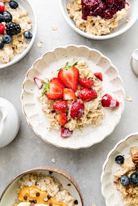 top down view of bowl of healthy oatmeal with strawberries and cream.