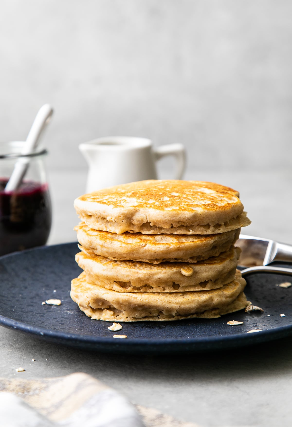 head on view stack of oatmeal pancakes on a plate with items surrounding.