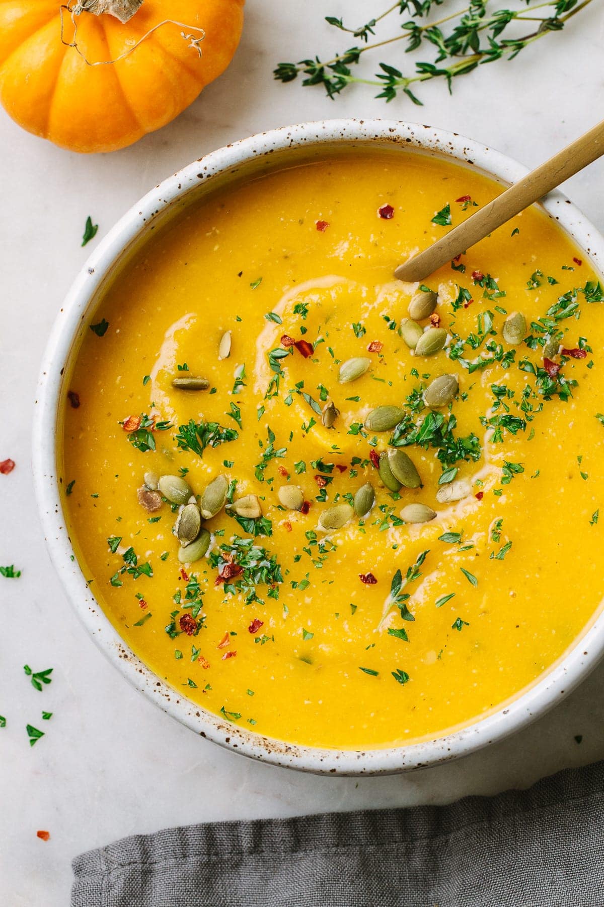 top down view of a serving bowl full of healthy and hearty vegan pumpkin soup with red lentils.